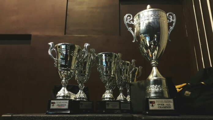 beberapa piala perak dan emas di permukaan kayu