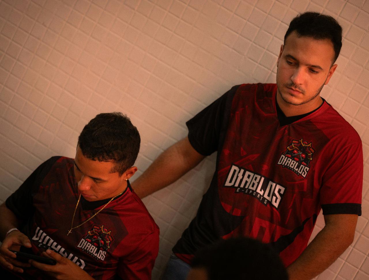 Dua pria dengan kaus merah dan hitam yang serasi bersandar.